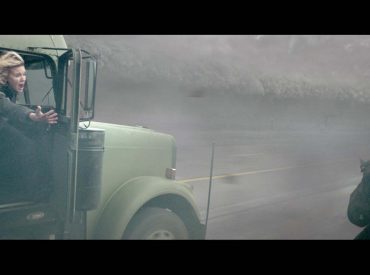 Mulher tentando ajudar outra pessoa a pular de um veiculo para outro, ambos em movimento. Cena do filme "no olho do furacão"