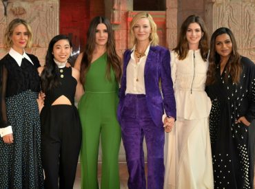 oito mulheres protagonistas do filme em um evento de gala, juntas lado a lado e de mãos dadas