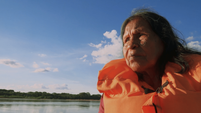 Fica Goiás: cena do documentário "Diriti de Bdé Buré" com foca em uma índia com colete salva vidas dentro de um barco em um rio