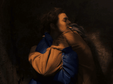 Foto divulgação do filme "Tesnota". Mulher jovem com um cigarro na boca abraçando uma pessoa