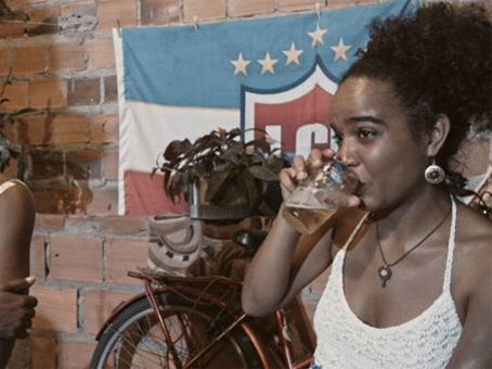 foto divulgação do filme "Café com Canela". Mulher negra tomando cerveja